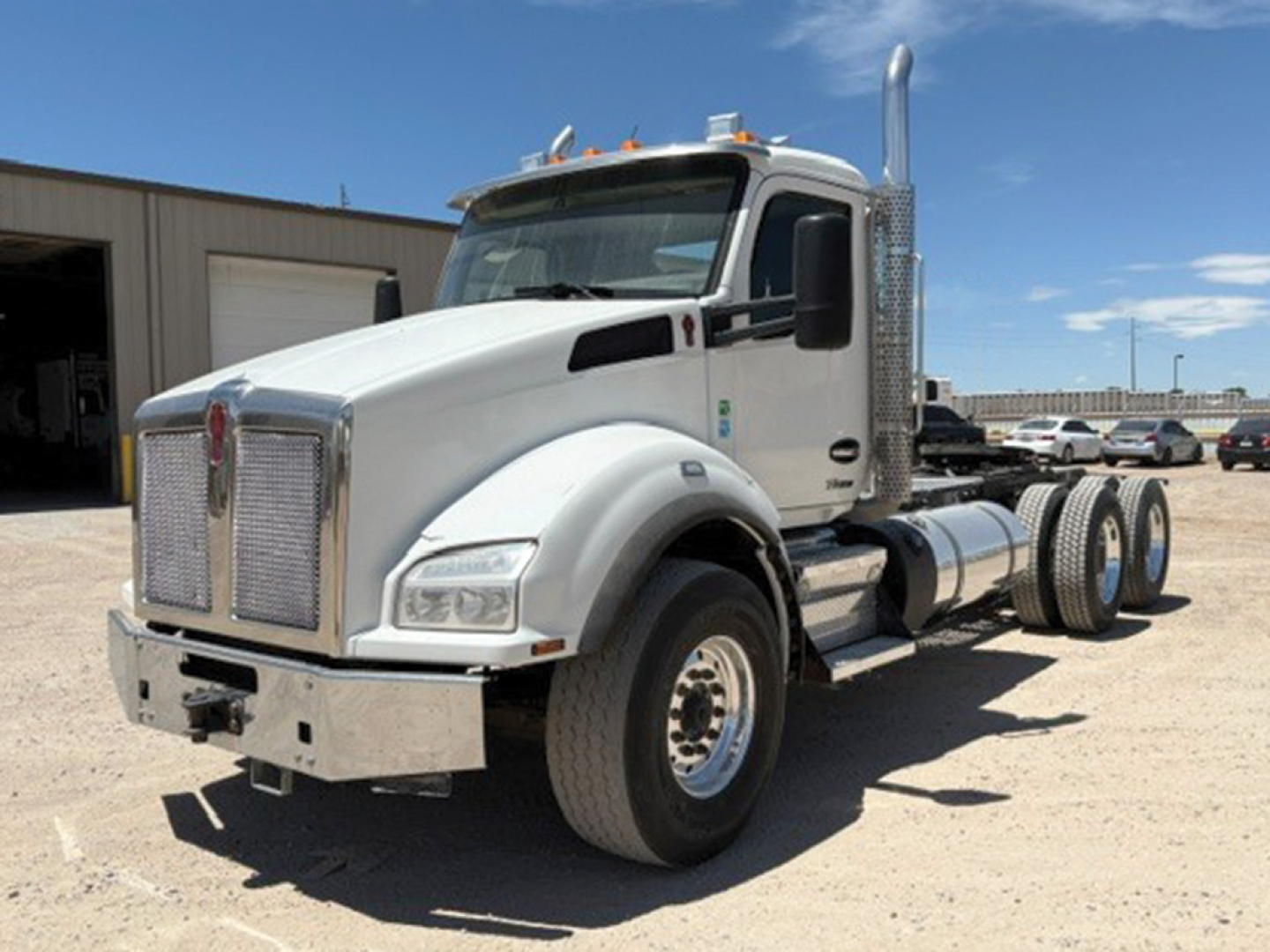 Kenworth T-880 tractor in white, side view showing high exhaust stack, dual rear axles, chrome grille, and cab with sleeper-less day cab.