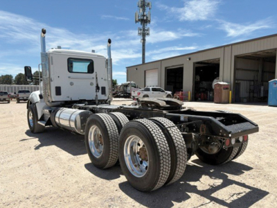 Kenworth T-880 cab and chassis in a lot showing rear triple axles and fuel tanks