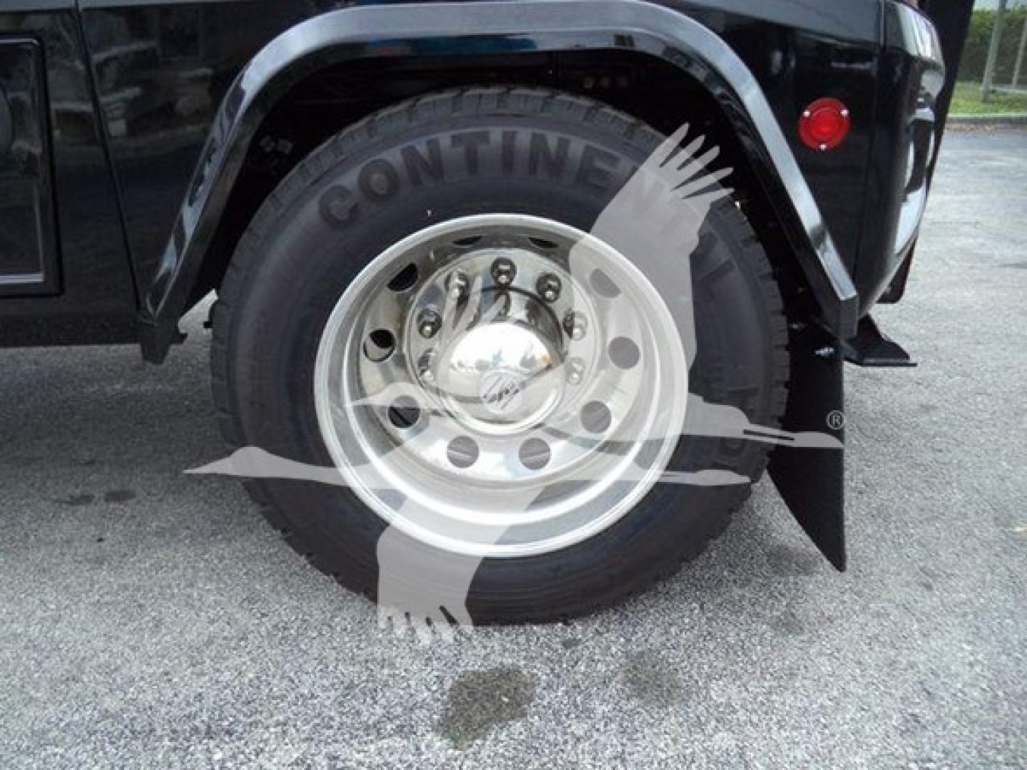 Front wheel and fender of a Freightliner M2 106 truck showing Conti tire and polished steel wheel with hub cap.
