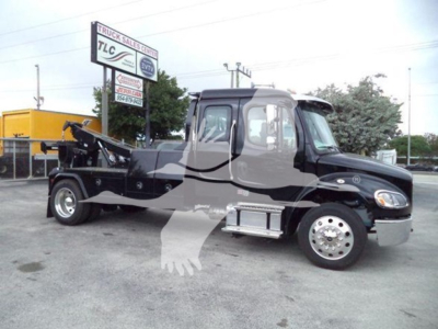 Freightliner M2 106 tow-wrecker truck side view with winch and body equipment visible.