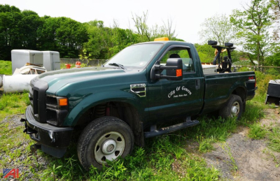 Ford F-250 XL regular cab pickup truck in green with utility equipment in bed, side view showing crew cab, front grille, and wheel