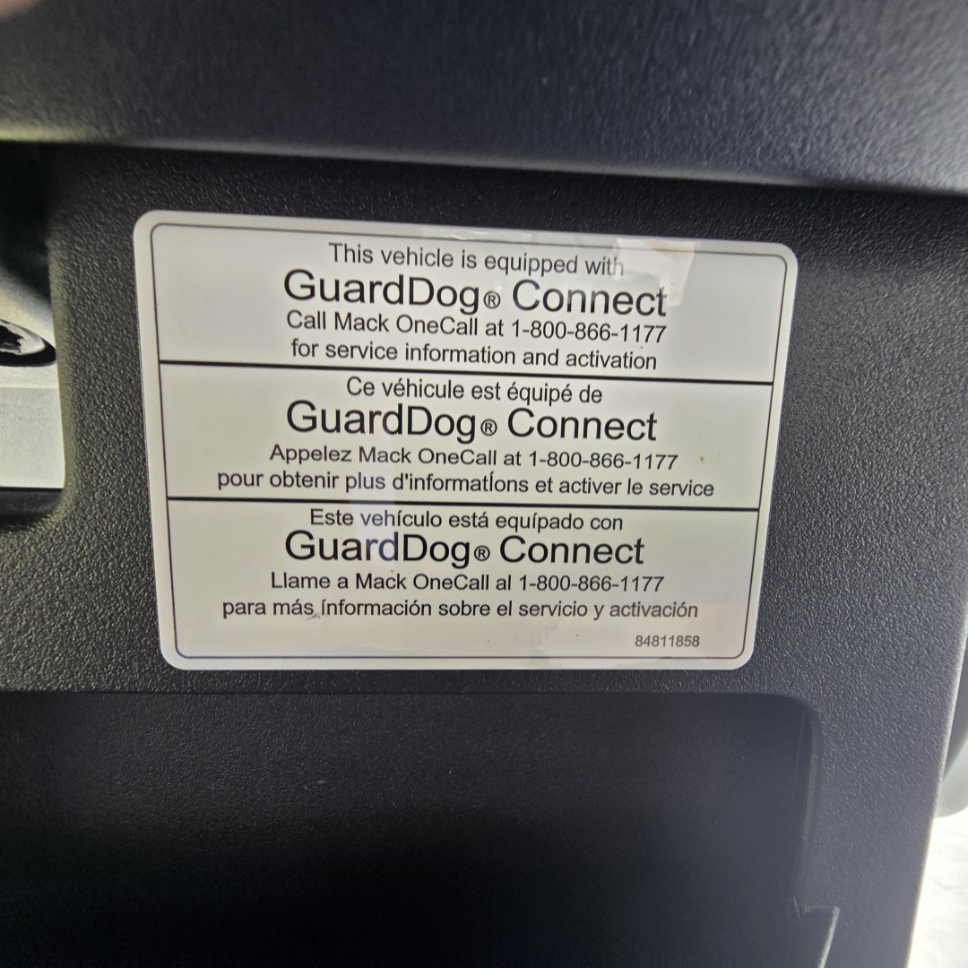 Sticker showing GuardDog Connect device label on Mack AN64T truck, with multilingual text and phone number for Mack OneCall service activation.