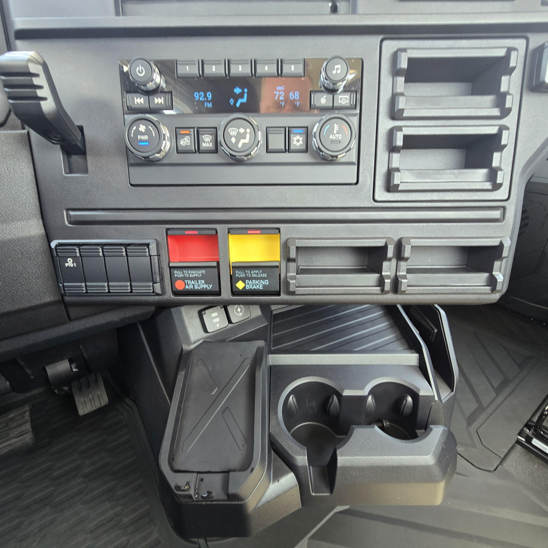 Truck dashboard interior showing climate controls, switch panels, cup holders, and storage compartments.