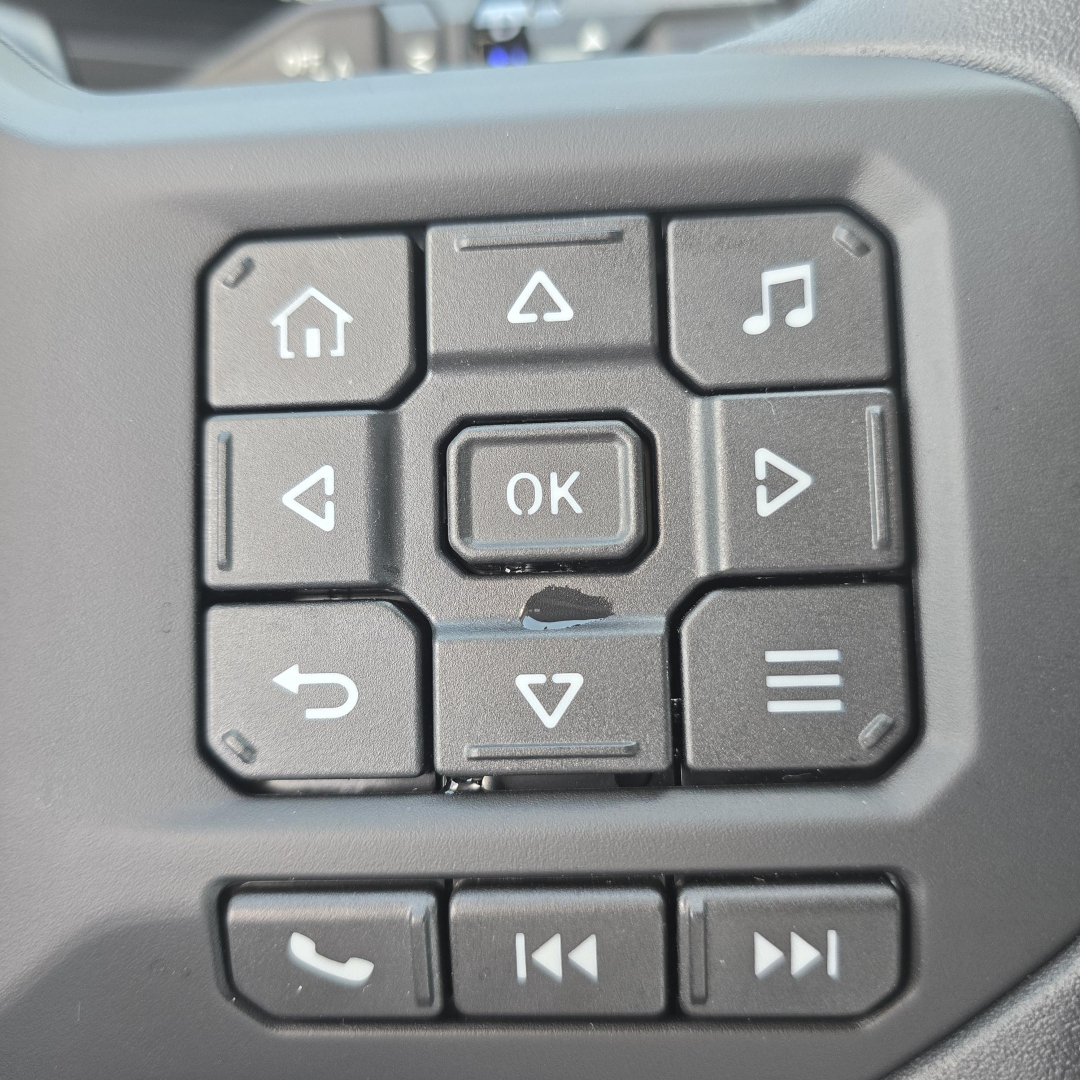Dashboard navigation keypad with OK button and navigation arrows, showing square keys and molded controls.