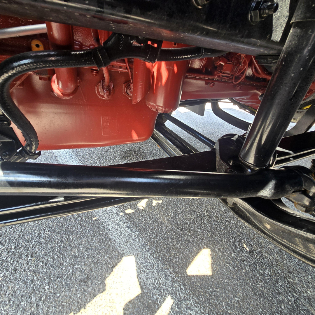 Mack AN64T engine bay showing red oil pan and black chassis components under the cab.