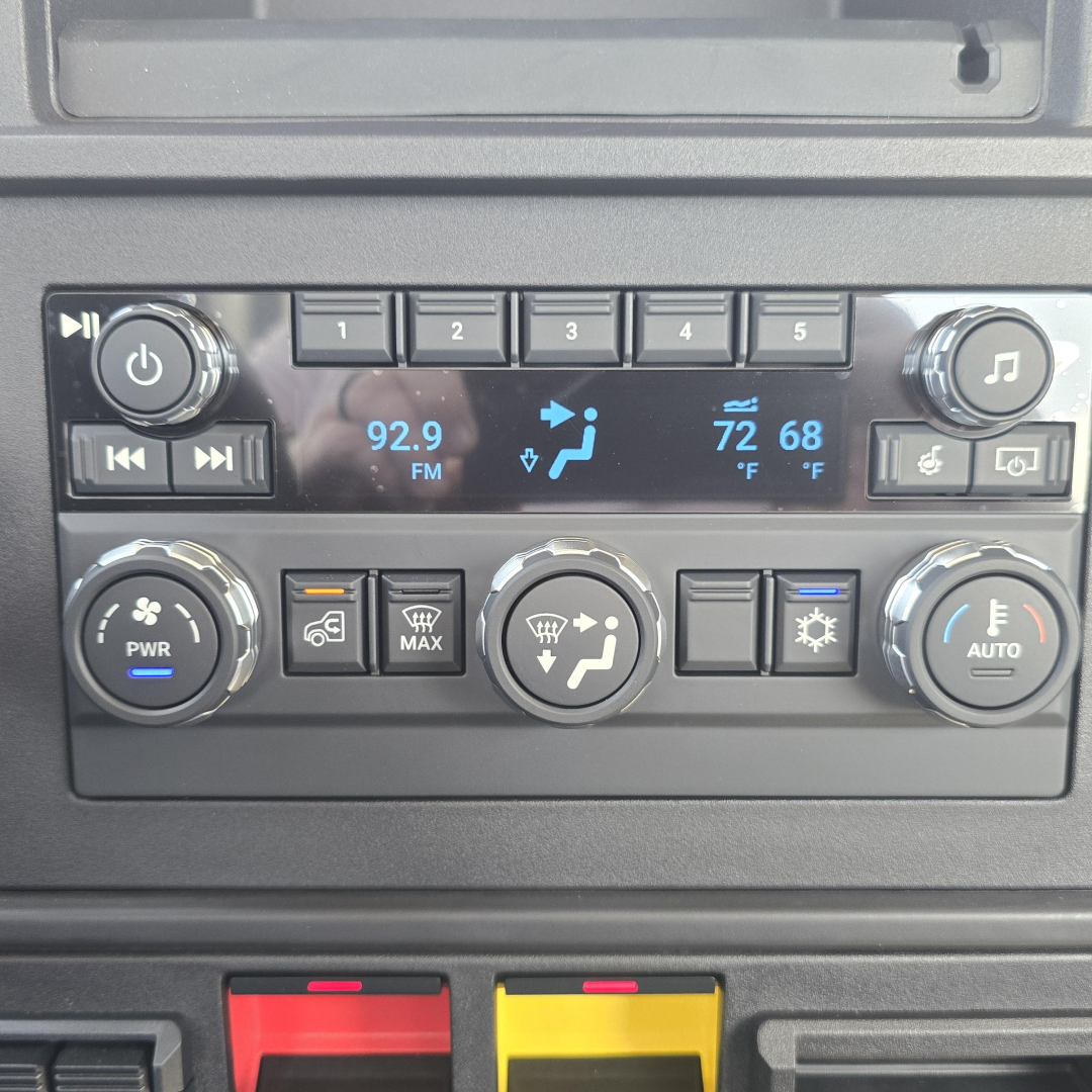 Truck interior control panel showing radio display with three rows of buttons, climate controls, and dials; Mack AN64T listing image