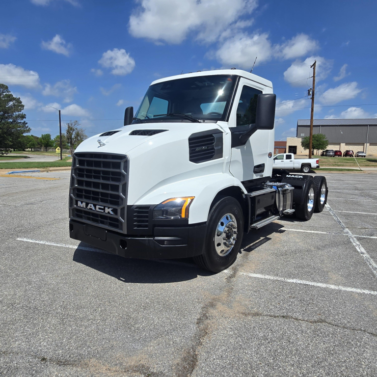 White Mack AN64T daycab tractor in a parking lot, front-left view. Visible text includes MACK on the grille, and the headlight area.
