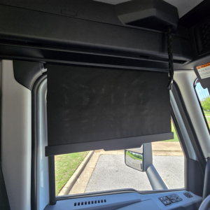 Truck cab interior showing sun visor and window area with dashboard controls, passenger-side view.