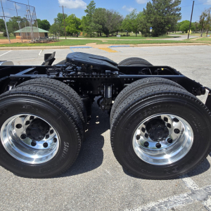Dual rear tractor axles and driveshaft on a new Mack AN64T conventional daycab showing tandem dual tires and chrome rims.