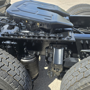 Mack AN64T cab chassis showing engine bay area with suspension and air filter canister visible, view of front wheel and frame members.