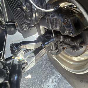 Front suspension and steering linkage of a new 2027 Mack AN64T truck showing control arms, steering knuckle, and wheel hub. Clear text on components not legible.