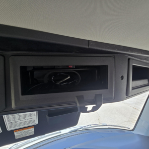 Truck interior showing overhead console with blank panel and wiring in recessed compartment above windshield; partial sun visor area visible.