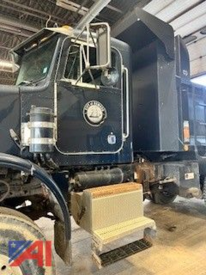 Peterbilt 357 dump truck cab with black paint, chrome mirrors, fuel/water separator canister on door, side steps, and dump bed in workshop.