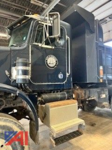 Peterbilt 357 dump truck cab with black paint, chrome mirrors, fuel/water separator canister on door, side steps, and dump bed in workshop.