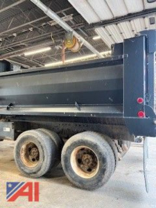 Peterbilt 357 dump truck side view showing dual rear wheels and cargo bed with hydraulic hoist in industrial setting.