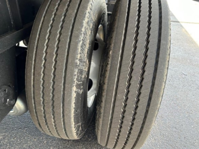 Dual rear tires of a utility flatbed trailer showing treaded tires with sidewalls and wheel hubs.