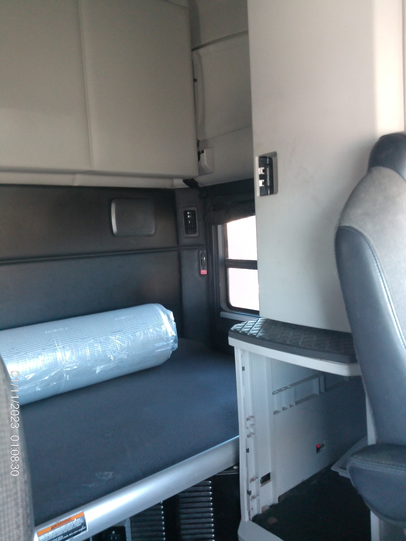 Kenworth T680 interior sleeper cab area with window, storage shelf, and part of driver seat visible.