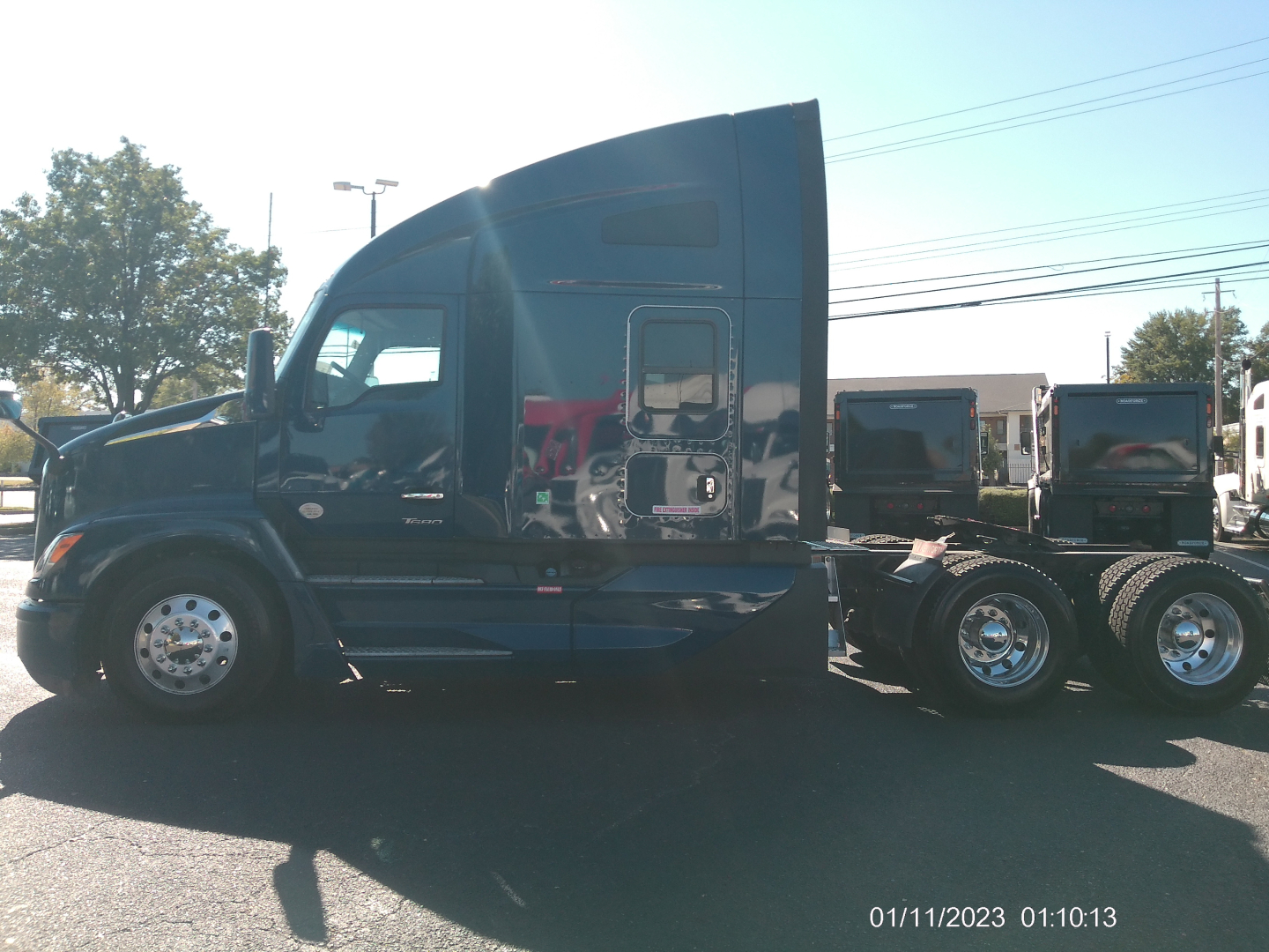 Kenworth T680 long-hood sleeper tractor in side profile with dark blue paint and chrome wheels.