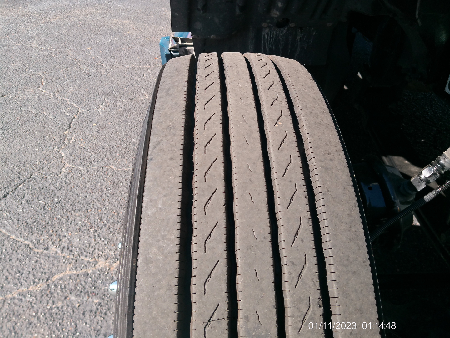 Tire and chassis area of a 2023 Kenworth T680 truck showing a single wide tire with tread grooves visible.