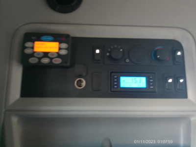 Kennworth T680 dashboard view showing control panel with keypad, small orange display, blue-lit LCD screen, and circular knobs.