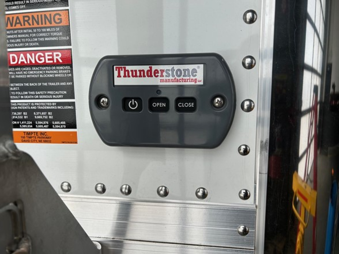 Thunderstone manufacturing control panel on a Timpte Super Hopper trailer showing POWER OPEN CLOSE buttons and warning labels with DANGER text.