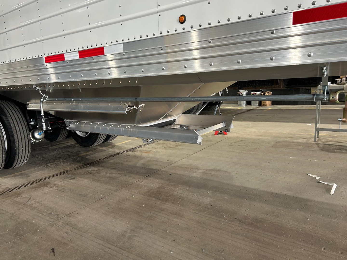 Trailer undercarriage showing lower side rail and suspension of a 2026 Timpte Super Hopper trailer with reflective striping and underbody support.