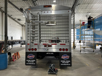 Timpté hopper trailer rear view showing vertical and horizontal bars, rear doors, mudflaps with Utility logos, license plate, and cheyenne wy trailer shop background.