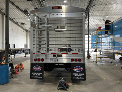 Timpte Super Hopper trailer back view showing rear doors, ladder, and bumper decals, utility logos, and license plate area.