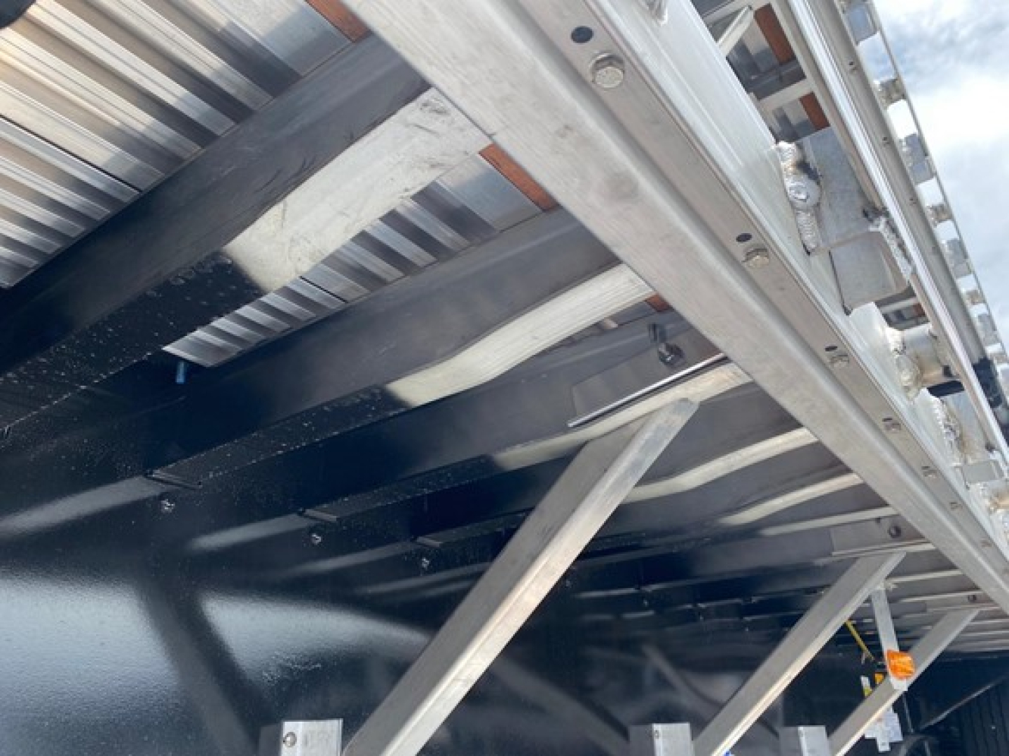 Trailer undercarriage showing structural members and support beams of a drop deck trailer.