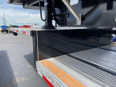 Deck area of a new utility combo drop trailer showing aluminum grip tread plate and side step with black painted frame.