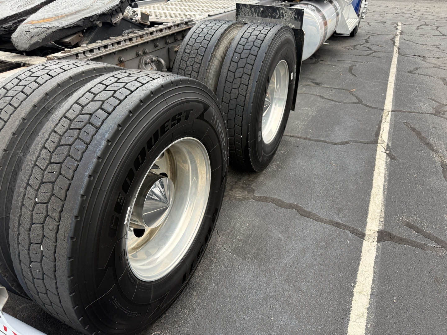 Kenworth W900L truck rear dual axle with large tires and rims, view of tandem axle section.