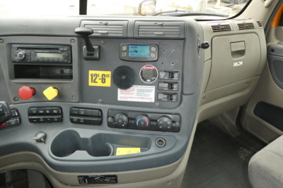 Dashboard interior of a 2017 Freightliner Cascadia 125 showing center console with controls, radio, cup holders, and a yellow '12-6' badge.