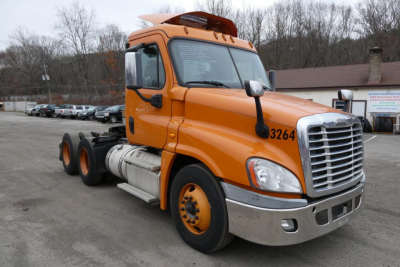 Orange Freightliner Cascadia 125 Daycab truck rear wheel view with cab number 3264, chrome grille, fuel tanks, and black chassis.