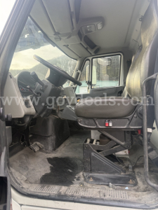 Large view of the truck cab interior showing steering wheel and driver seat with floor area and pedals.