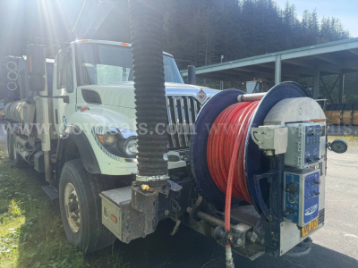 International WorkStar 7500 vacuum truck showing reel hose setup on front with truck cab and equipment in yard.