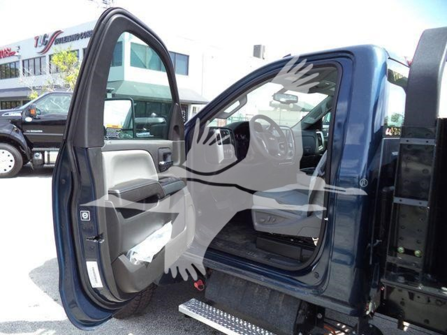 Truck cab door open on blue Chevrolet Silverado 6500HD in showroom lot.