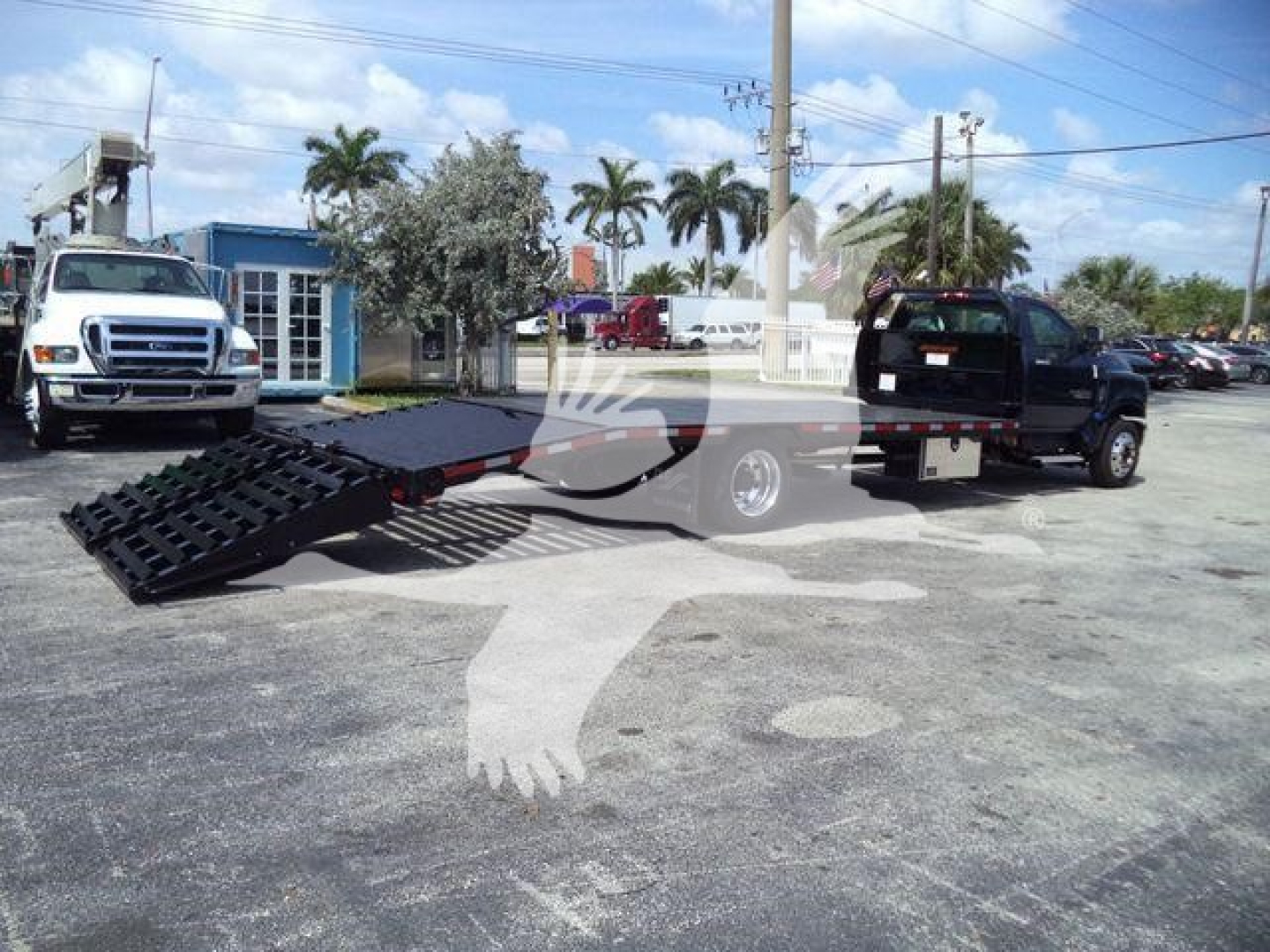 2023 Chevrolet Silverado 6500HD in a dealership lot showing a ramp equipment with a black metal ramp attached to a trailer hitch.