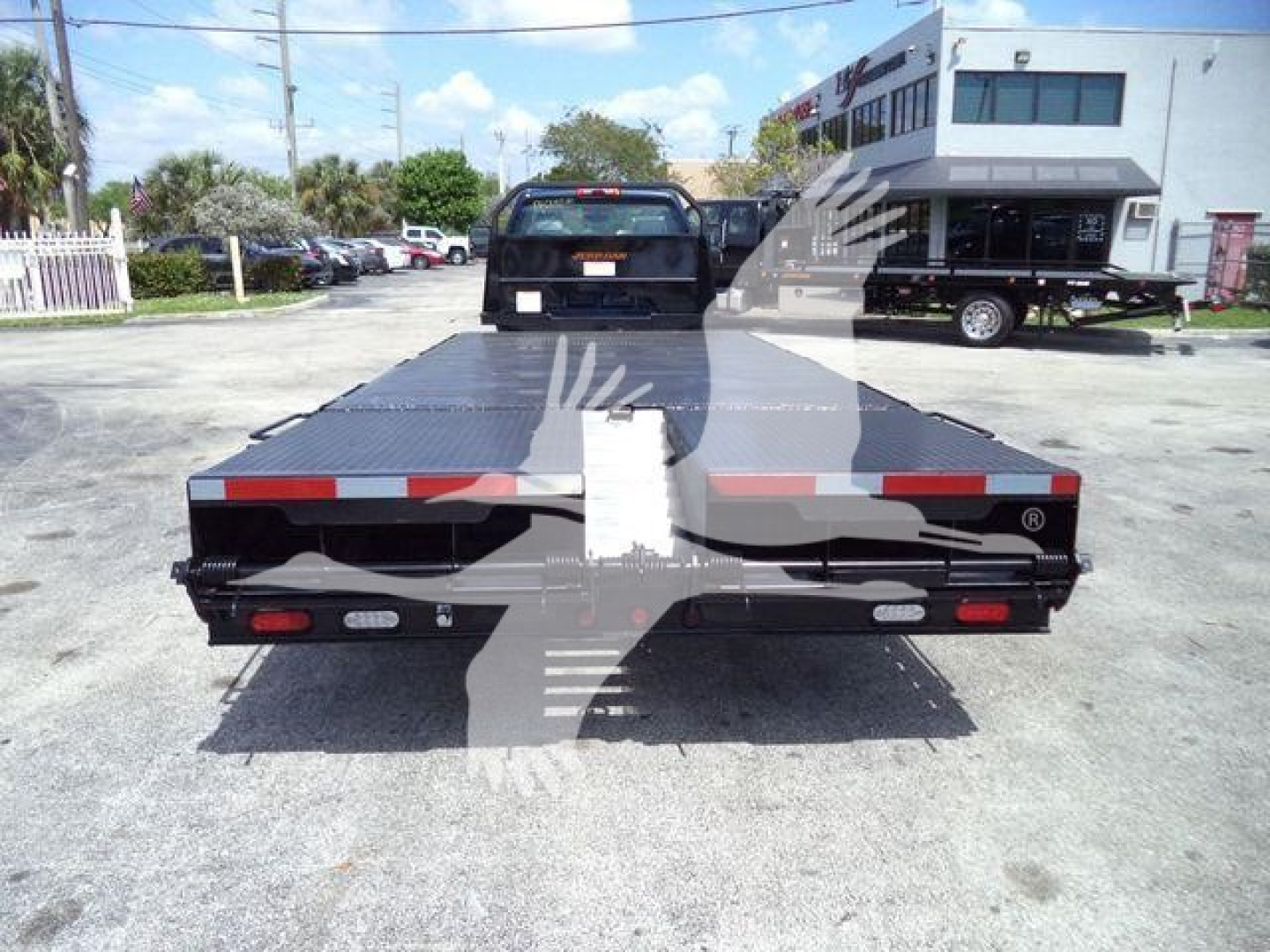 Flatbed truck bed back view showing rear lights and reflective tape on Silverado 6500HD chassis with a ramp style deck.