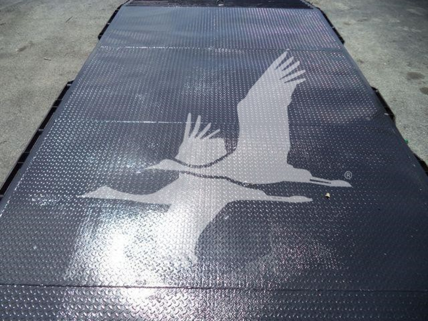 Flatbed showing raised chevy/angel emblem graphic on diamond plate surface.