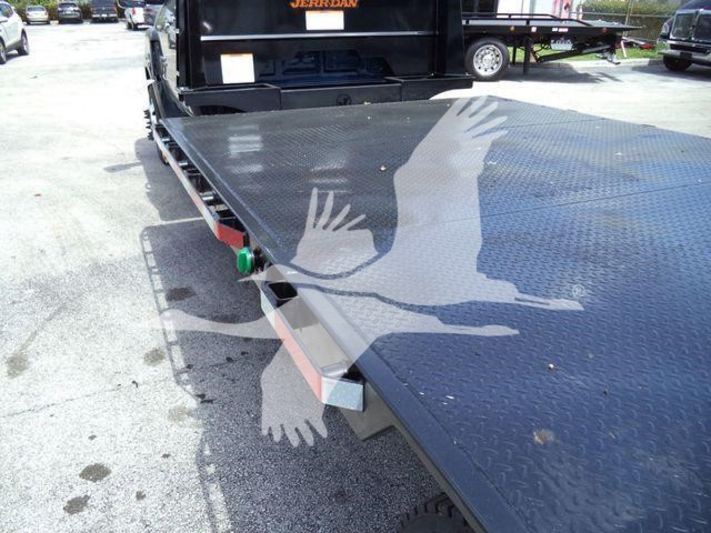 Chevrolet Silverado 6500HD flatbed truck showing diamond plate deck and ramp with green pin and safety chain.