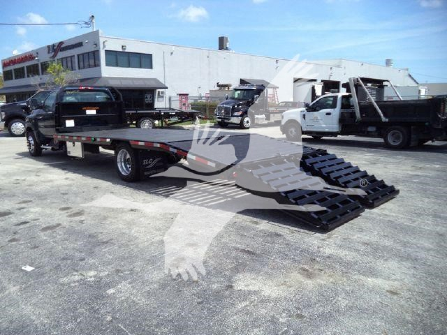 Chevrolet Silverado 6500HD truck in yard with flatbed tilt equipment and ramp loading ramps visible.