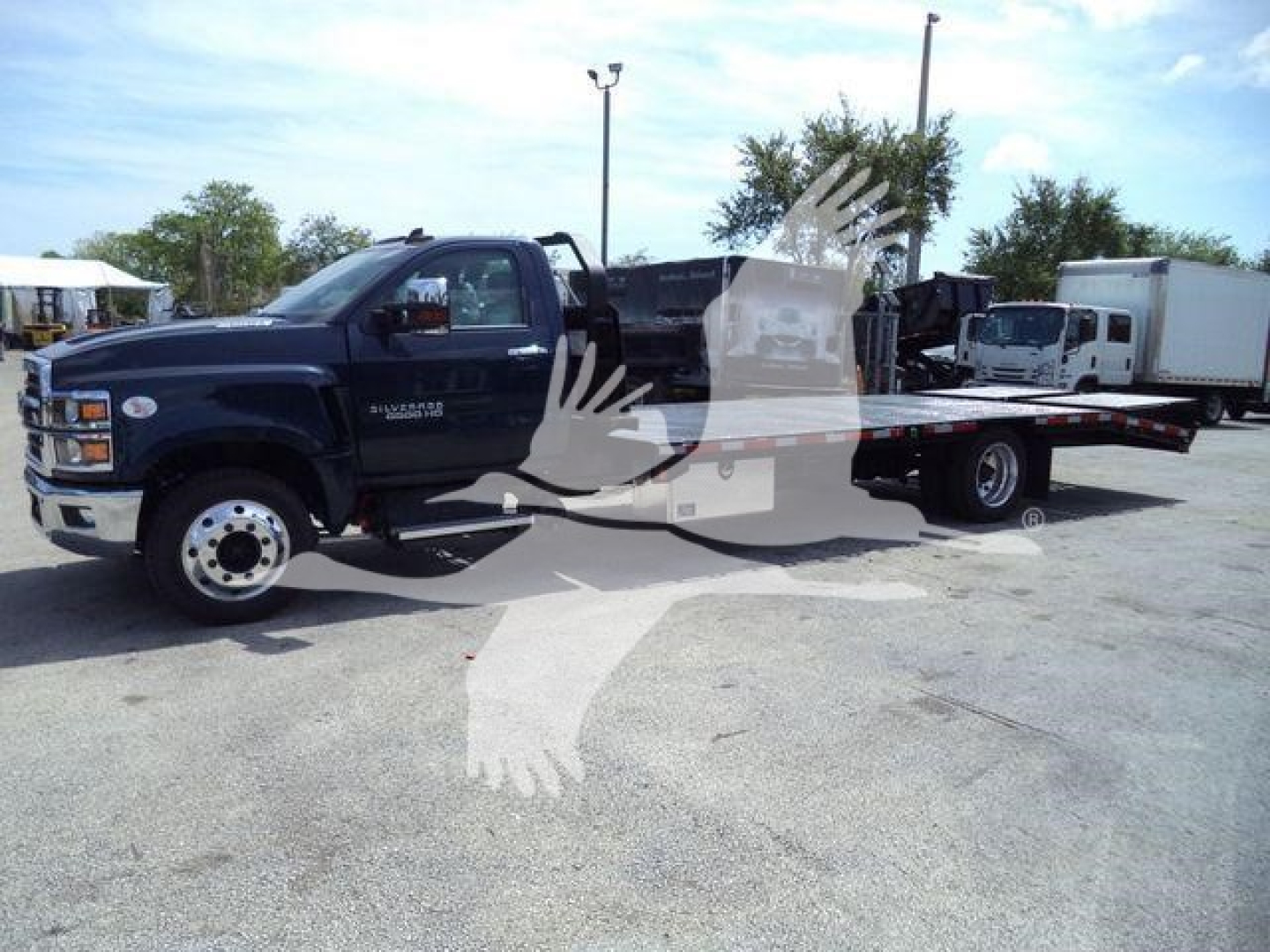 Flatbed tow truck/haul vehicle in a dealership lot with Silverado 6500HD badge visible on cab.