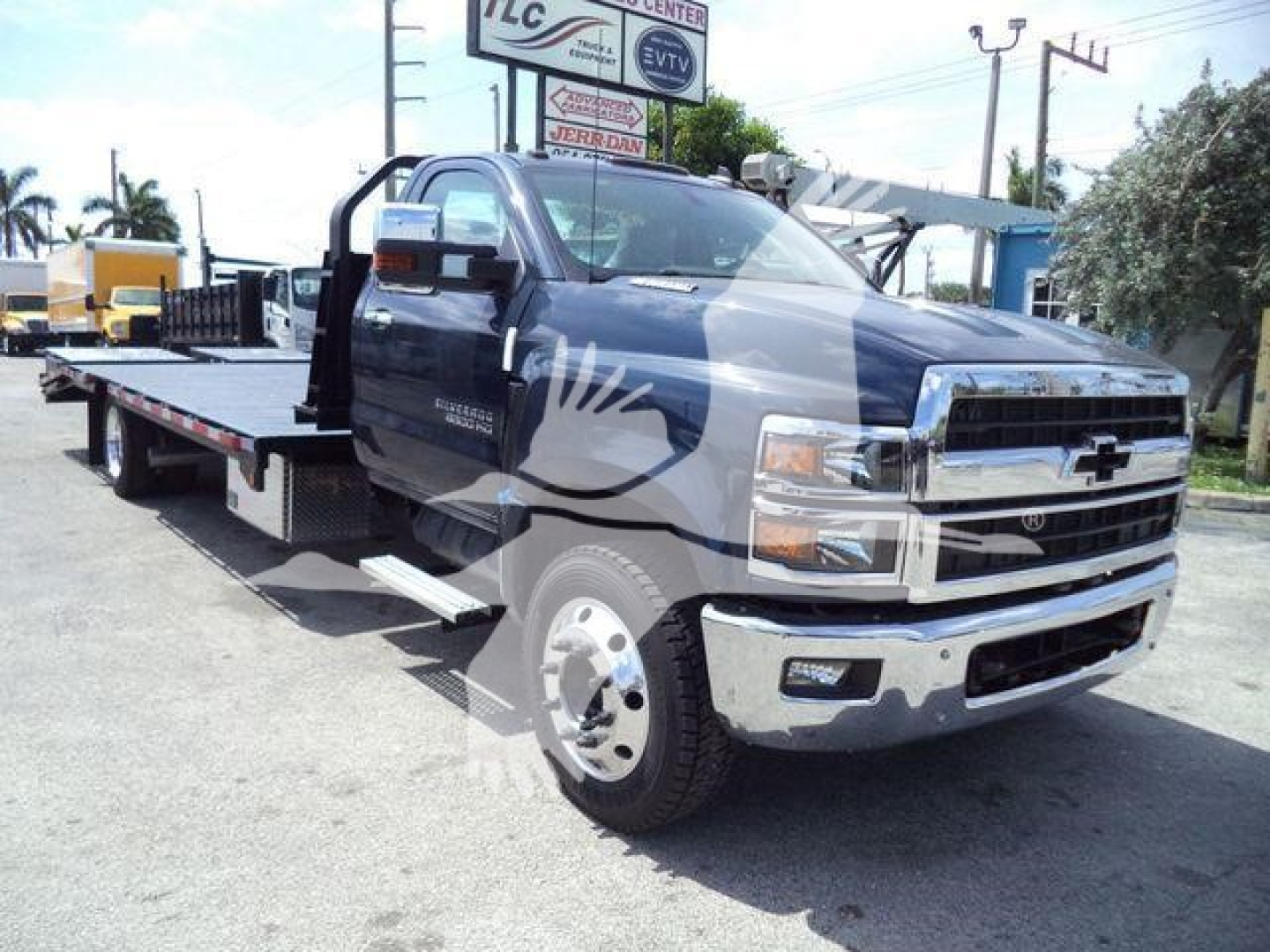 Chevrolet Silverado 6500HD tow truck flatbed with prominent chrome bumper and extended cab, front grille visible.