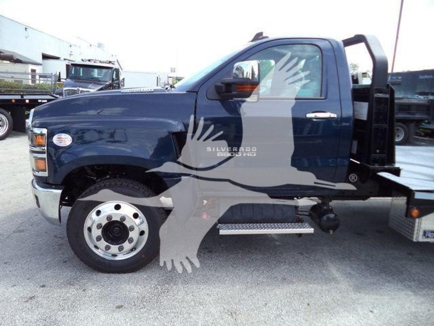 Chevrolet Silverado 6500HD stake bed truck side view showing front wheel and cab with logo text