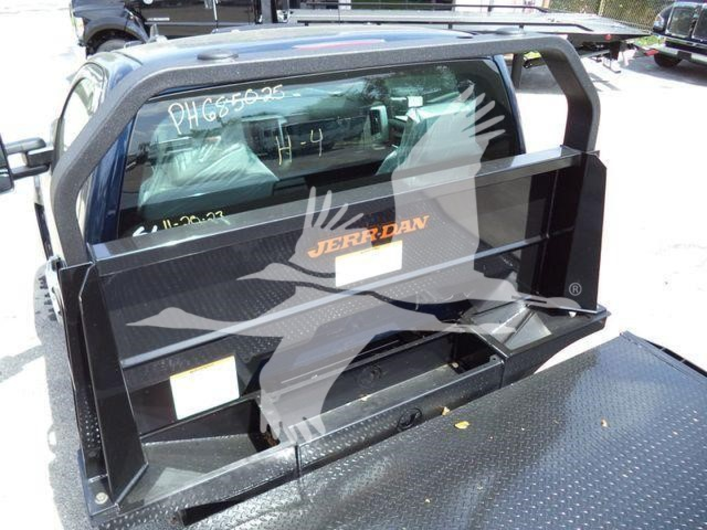 Chevrolet Silverado 6500HD truck bed with Jerr-Dan ramp nose and flatbed platform, rear view showing storage compartments and tailgate area.