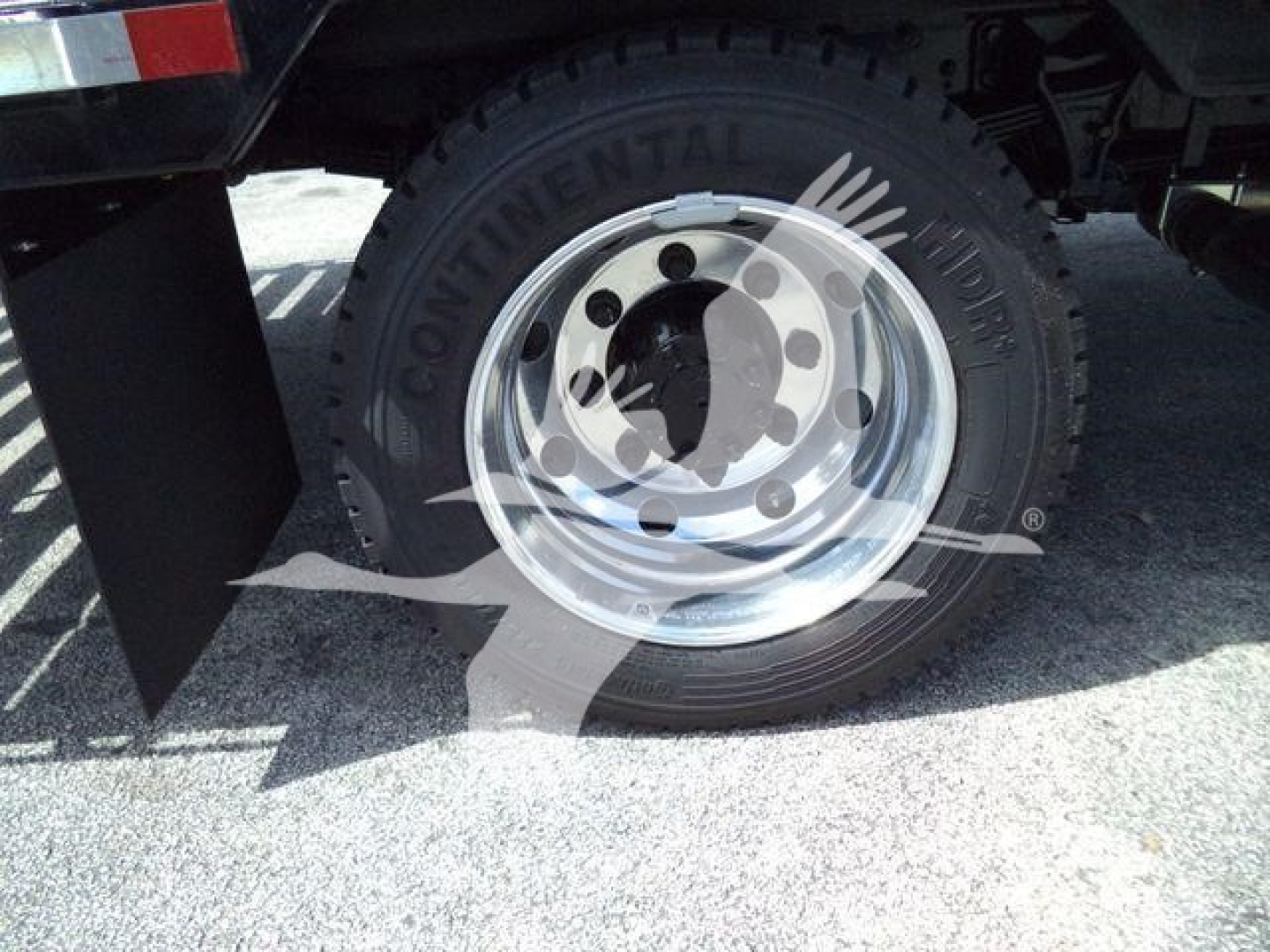 Truck wheel close-up on a Silverado 6500HD showcasing a Continental tire mounted on a polished steel rim with black undercarriage and mudflap.
