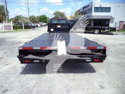 Flatbed truck bed back view showing rear lights and reflective tape on Silverado 6500HD chassis with a ramp style deck.