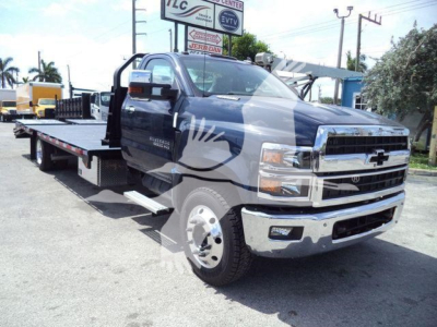 Chevrolet Silverado 6500HD tow truck flatbed with prominent chrome bumper and extended cab, front grille visible.