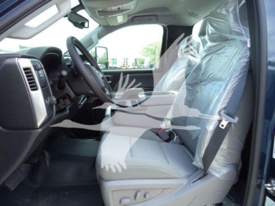 Vehicle interior of a 2023 Chevrolet Silverado 6500HD cab showing front seats and steering wheel, with protective plastic on the passenger seat and plastic-wrapped seat covers.