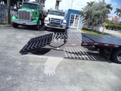 Truck ramp or loading ramp on a trailer with a Chevrolet Silverado 6500HD in background and other trucks nearby.